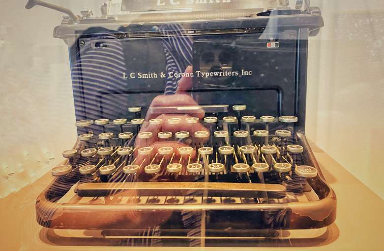 The poet's face is reflected on the keyboard of an old typewriter.